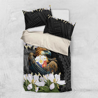 Black bedding set laid flat: duvet and pillowcases with eagle crest and white blossoms