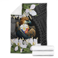 Folding black blanket showing eagle crest, white blossoms, and green leaf accents