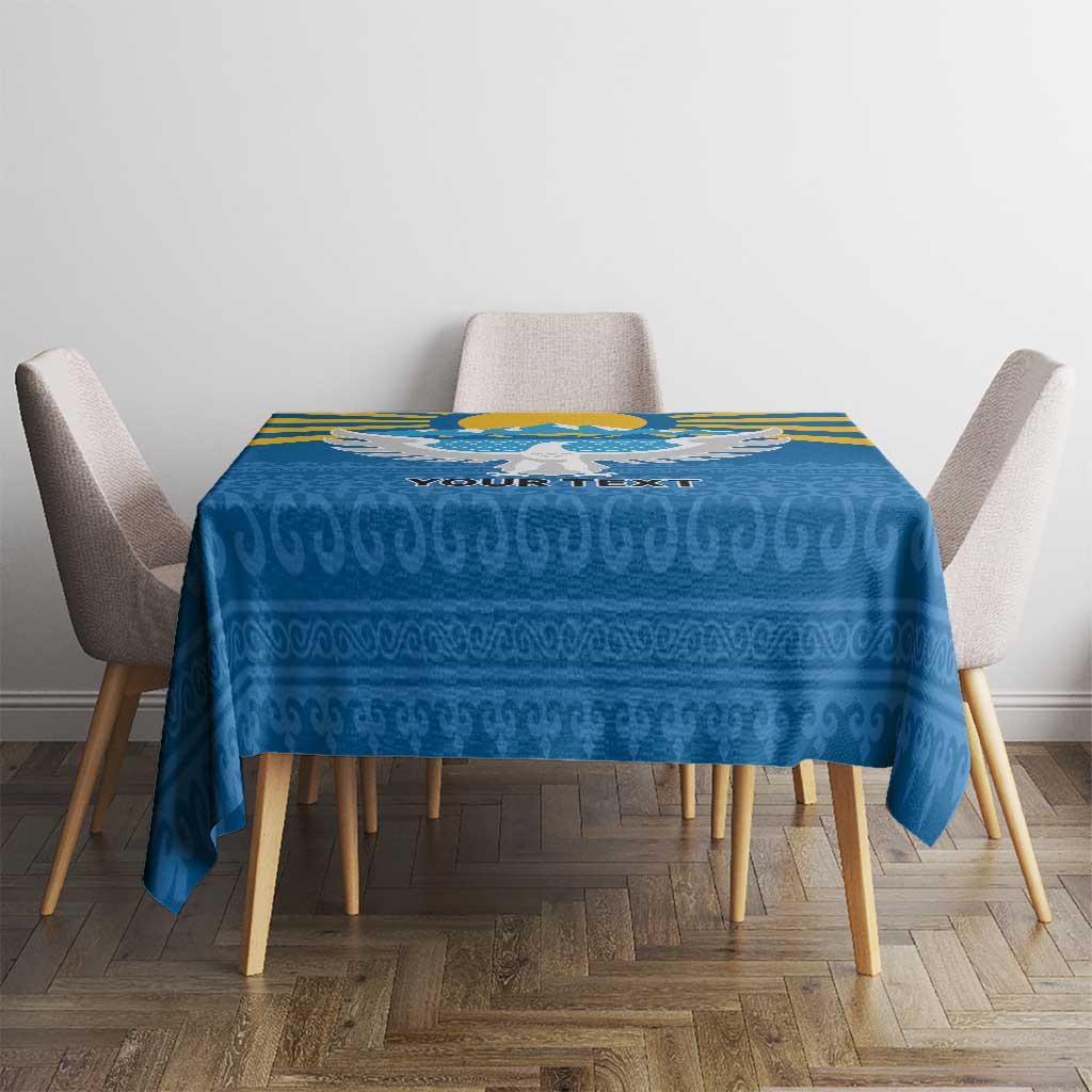 Square blue personalized tablecloth with mountain and falcon motif, on dining table.
