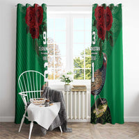 Green curtain panels with red rose motif and bird print, hung with a chair and small table