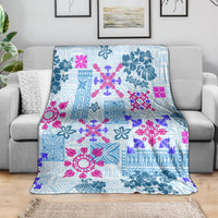 Blue tapa quilt blanket with floral tribal pattern, spread over gray sofa