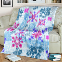 Blue tapa quilt blanket with floral tribal pattern, draped across cream couch