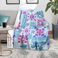 Blue tapa quilt blanket with floral tribal pattern, folded on living room chair