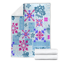 Blue tapa quilt blanket with floral tribal pattern, folded with rolled white towels