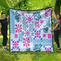 Blue tribal quilt with magenta floral and geometric motifs, fully spread on grass.