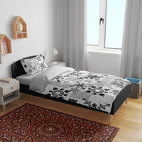 Black-and-white tribal quilt bedding set on bed with two patterned pillows
