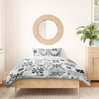 Black-and-white patterned quilt bedding set with two pillowcases on wooden bed