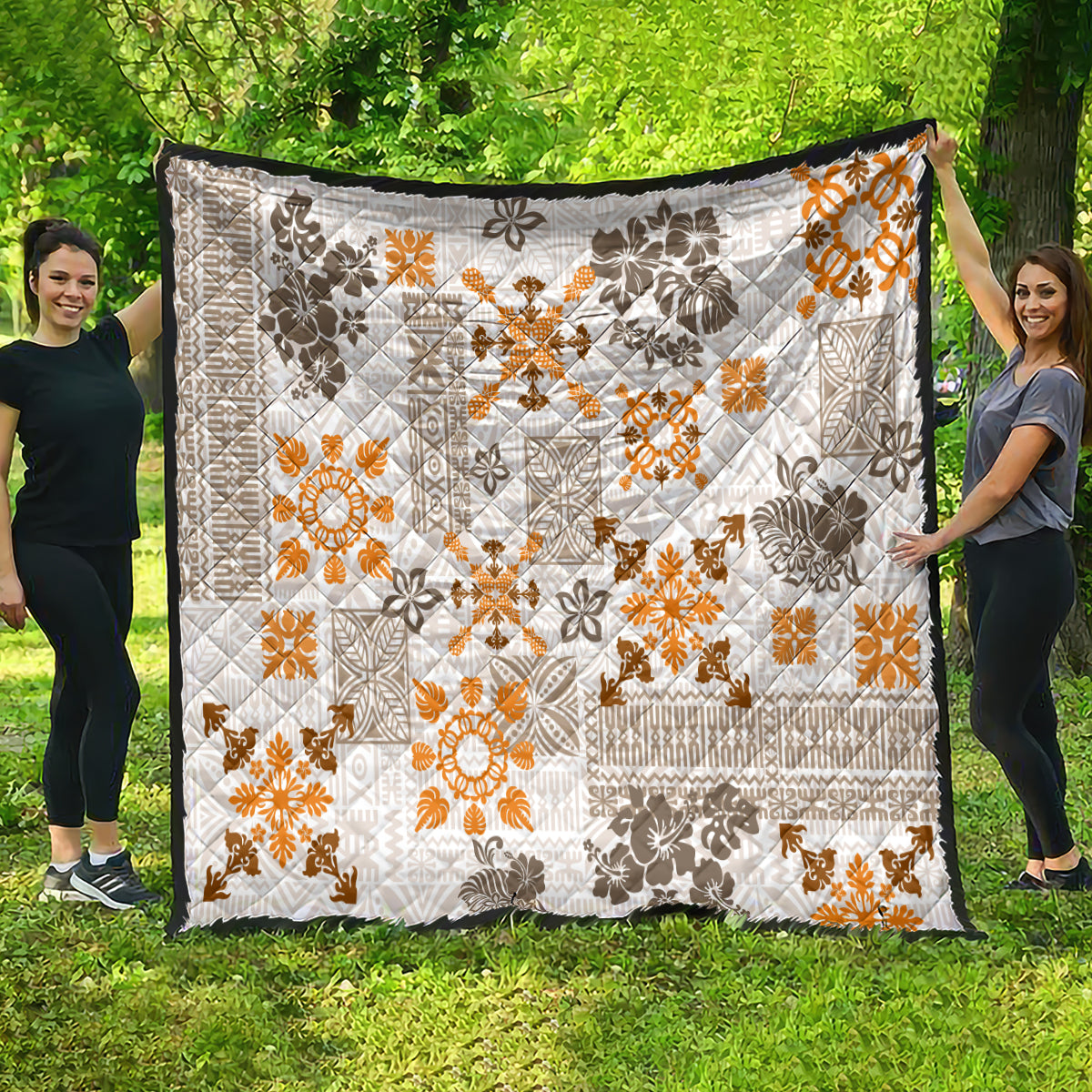 Hawaiian tapa quilt spread on grass, white fabric with orange and dark patterned squares