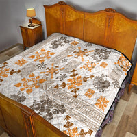 Quilted bedspread with white base, orange floral tapa motifs, and dark geometric accents