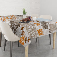 Rectangular tablecloth draped over dining table, tapa tribal print in brown and orange.