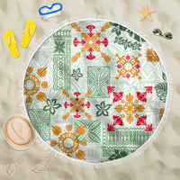 Round beach blanket with white fringe and green quilt pattern, red orange floral motifs