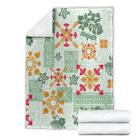 Green tapa tribal blanket with multicolor floral and geometric quilt motifs, folded stack