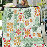 Green Hawaiian quilt with white base and orange, red, and green tapa tribal floral pattern