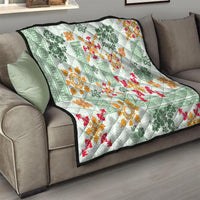 Green tapa tribal quilt draped on sofa, with white center and orange and red decorative patterns