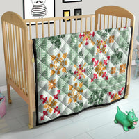 Green Hawaiian quilt on wooden baby bed, with tapa tribal motifs in red and orange