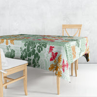 Green patterned tablecloth draped over dining table with tapa, floral, and animal motifs