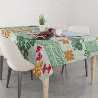 Green quilt-pattern tablecloth with tapa tribal motifs and bright red, orange accents
