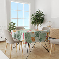 Green quilt-style tablecloth with tapa tribal pattern and multicolor floral accents