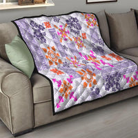 Violet quilt on a sofa with white tapa pattern and orange and magenta floral starbursts
