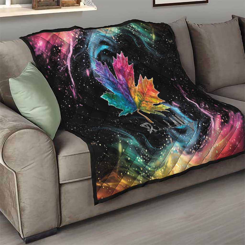 Black quilt blanket on gray sofa with rainbow maple leaf and colorful galaxy swirl