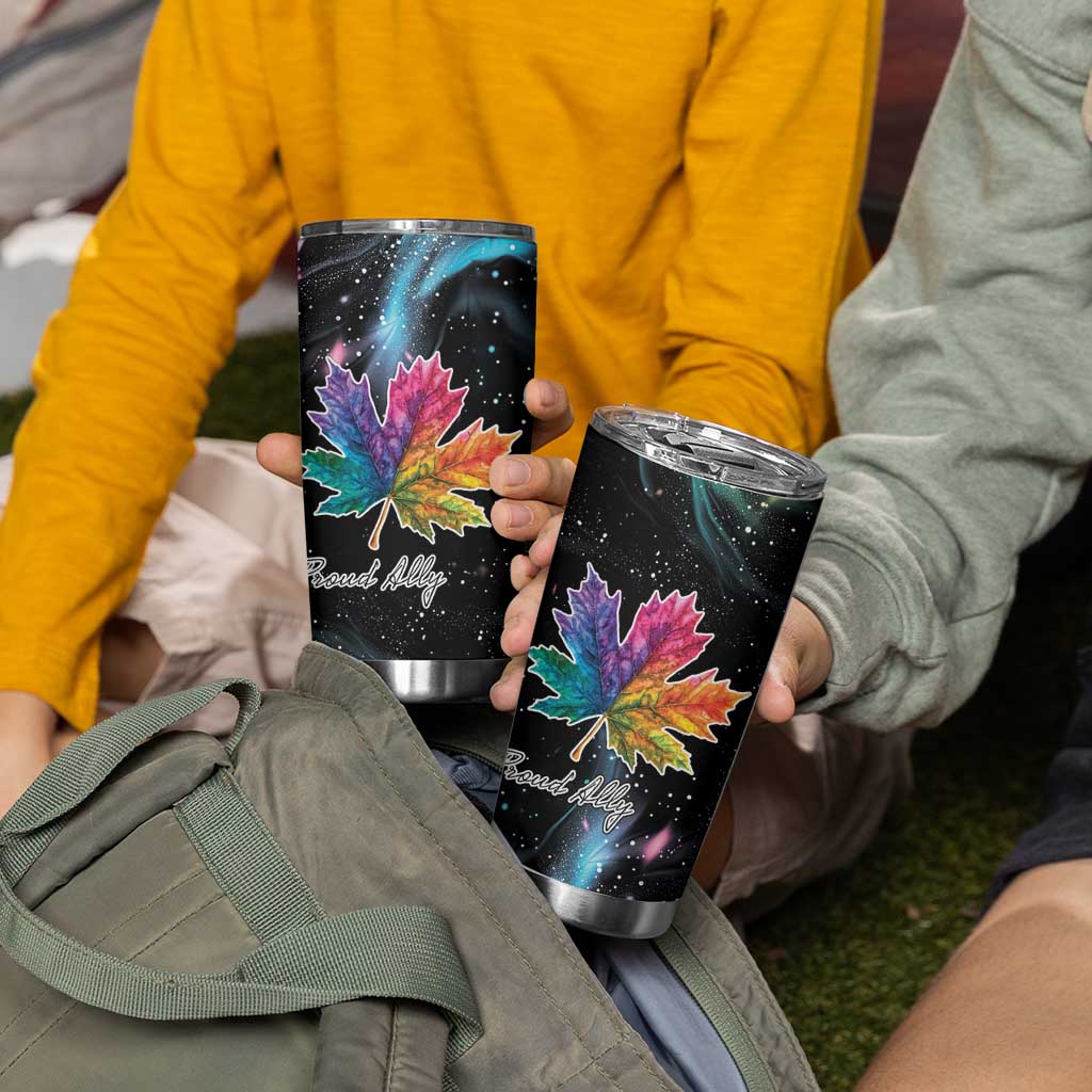 Two black tumblers held outdoors, each with colorful maple leaf and galaxy print.