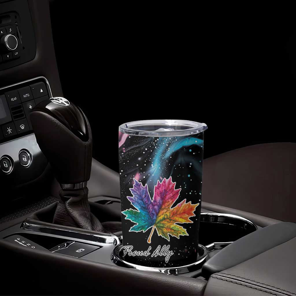 Black tumbler cup with maple leaf galaxy print and clear lid on car console.