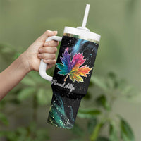 Black insulated tumbler with handle, rainbow maple leaf galaxy artwork, held in hand
