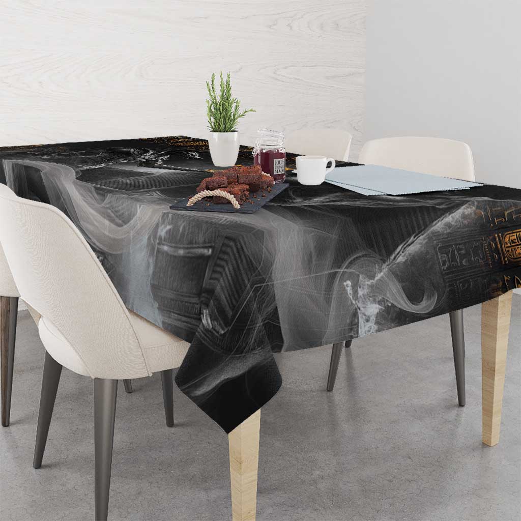 Black tablecloth featuring Anubis face and gold symbols, wrinkled over tabletop.