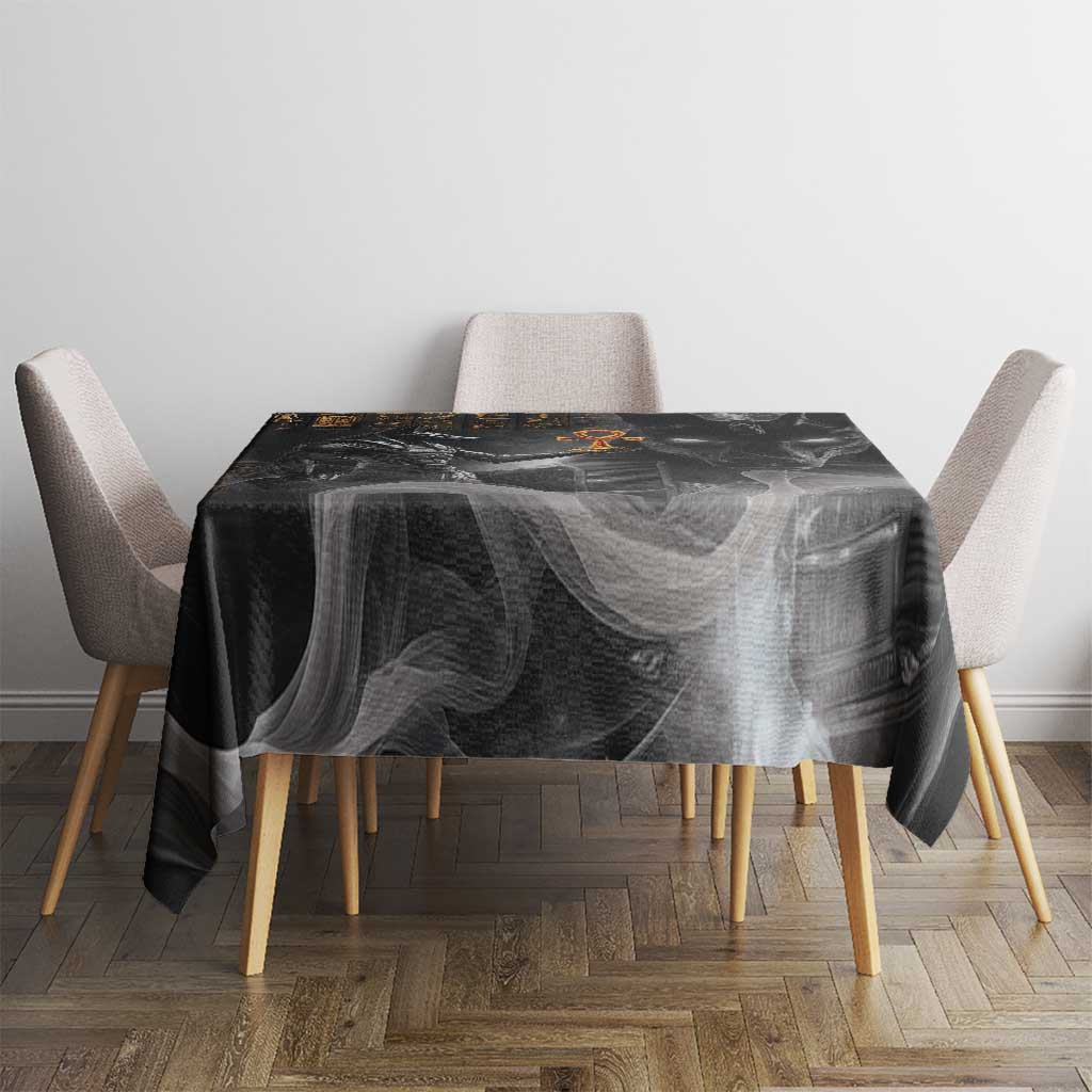 Black tablecloth with Anubis design and gold symbols on square dining table.