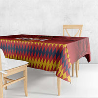 Red and multicolor diamond-pattern tablecloth draped over a dining table with corner fall