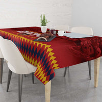Red tablecloth with yellow-and-navy geometric diamond pattern and printed crest on the edge
