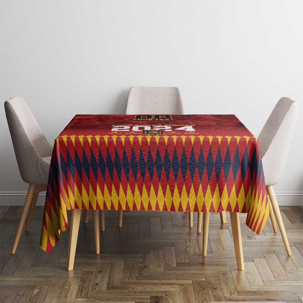 Red rectangular tablecloth featuring a yellow, navy, and gold diamond pattern and crest at center