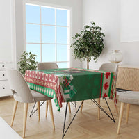 Green Christmas moose tablecloth with red and white striped edge and evergreen decor