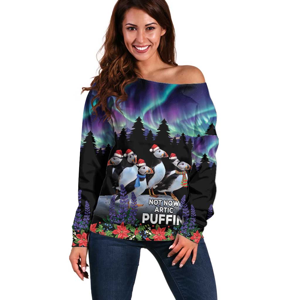 Women’s black off-shoulder sweater with arctic puffin graphic, aurora lights and snow scene