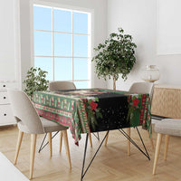 Green holiday tablecloth with goat and Santa scene, red floral border on dining table