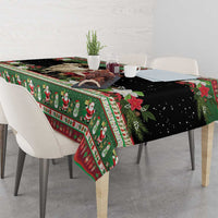 Green patterned tablecloth with goat and Santa, red trim and snowflake accents