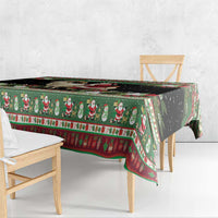 Green goat-and-Santa tablecloth with red border, draped over wooden table