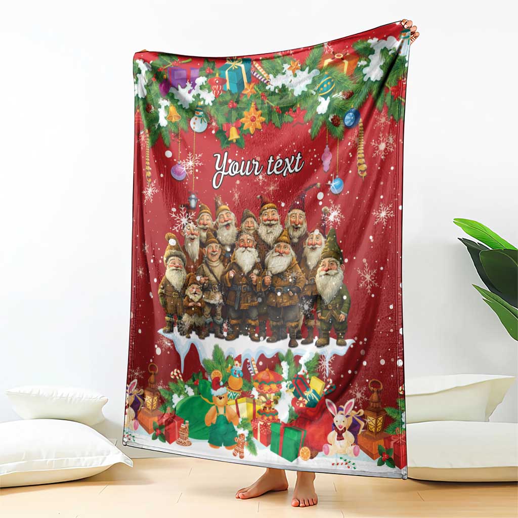 Personalized red holiday blanket printed with gnomes, snowflakes, gifts, and “Your text,” standing on floor