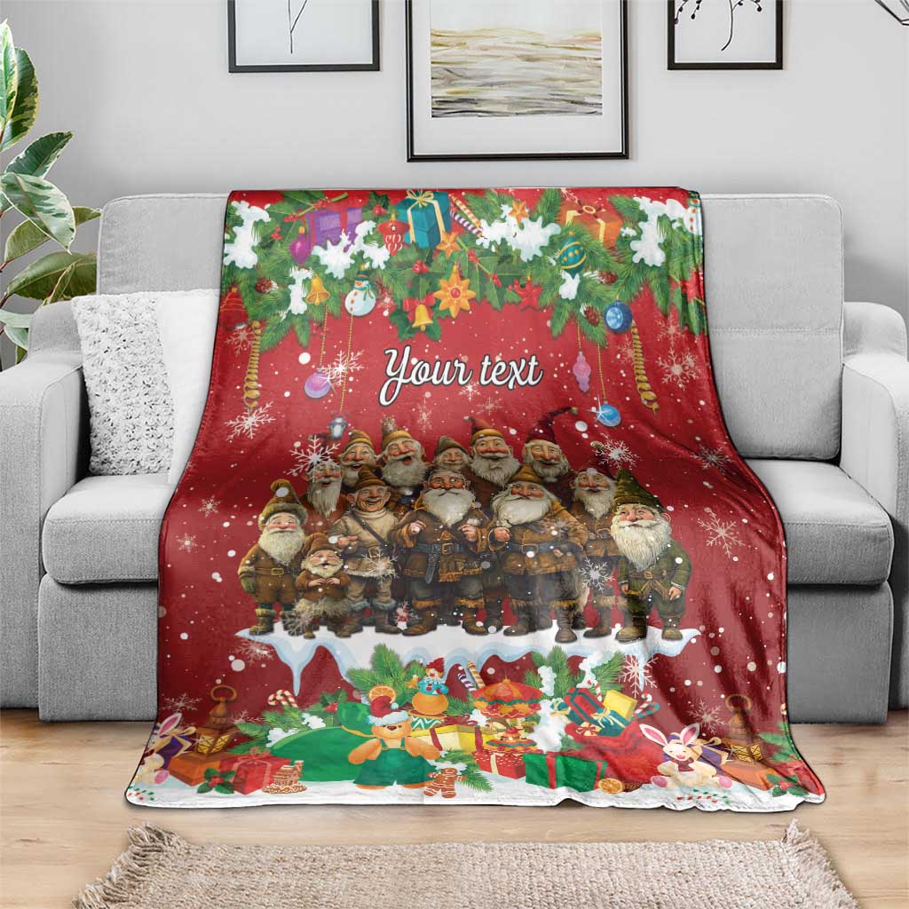 Personalized red holiday blanket featuring a gnome group under greenery and “Your text,” on a gray sofa