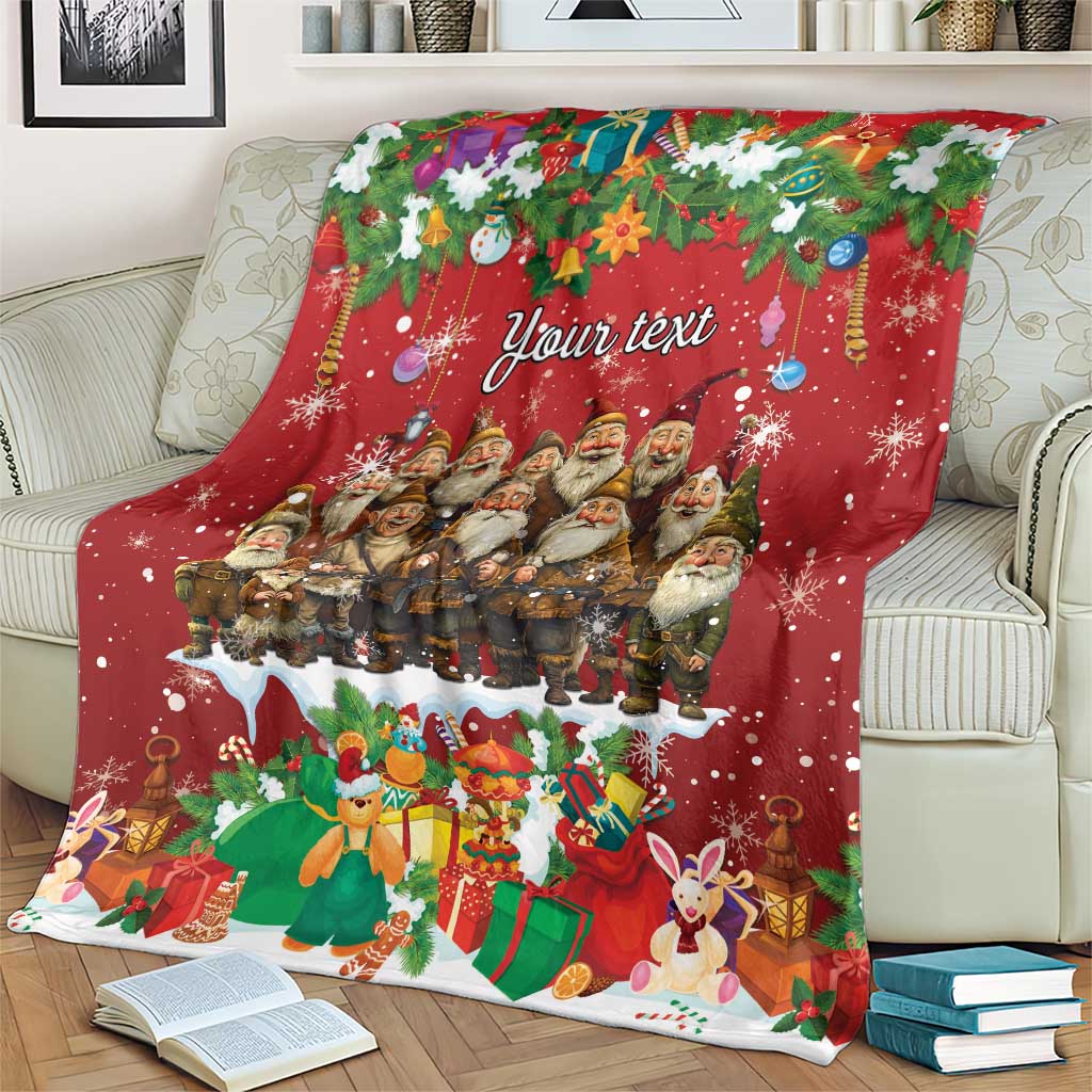 Personalized red holiday blanket with gnomes, gifts, holly, and “Your text,” spread on a couch
