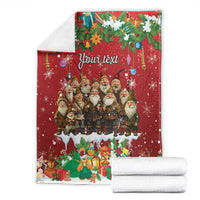 Personalized red holiday blanket with gnomes and “Your text,” shown folded with stacked white towels