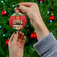 Hand holding a red round ceramic Christmas ornament with hanging loop and yule lads design