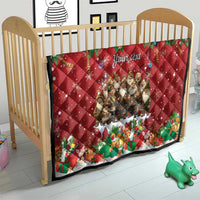 Red personalized quilt on wooden crib with "Your text" and Yule characters, quilted diamonds.