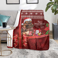 Red Christmas blanket with cartoon hippo, holiday message text, and snowflake border design