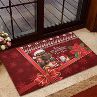Red rubber Christmas doormat with cartoon cow in plaid scarf, gifts, and poinsettia leaves
