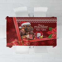 Red Christmas tablecloth flat lay with cow graphic, ribbon, snowflakes, and text.