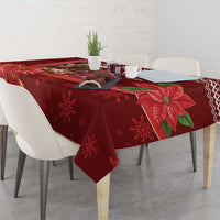 Red Christmas tablecloth on dining table with poinsettia and snowflake pattern.