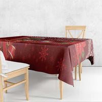 Red Christmas tablecloth draped over table edge with snowflake and ribbon design.