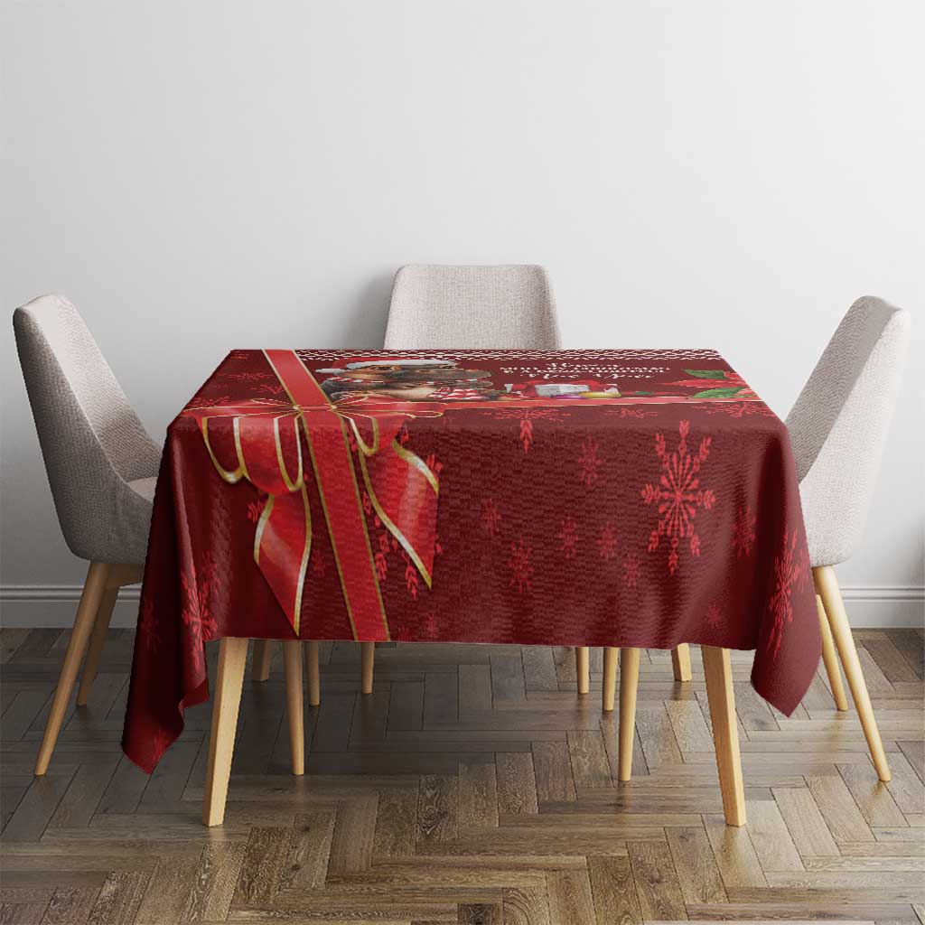 Red Christmas tablecloth on square table with poinsettia and snowflake motifs.