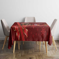 Red Christmas tablecloth on square table with poinsettia and snowflake motifs.